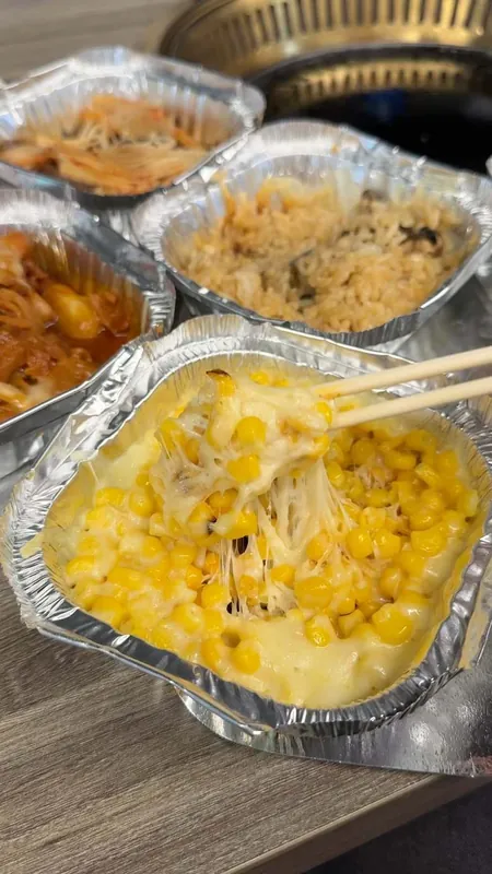 Cheesy baked corn lifted with chopsticks